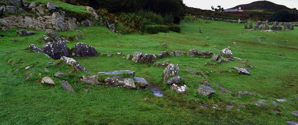 The remains of the joined stone huts with the Drombeg Stone Circle upper right - The Irish Place