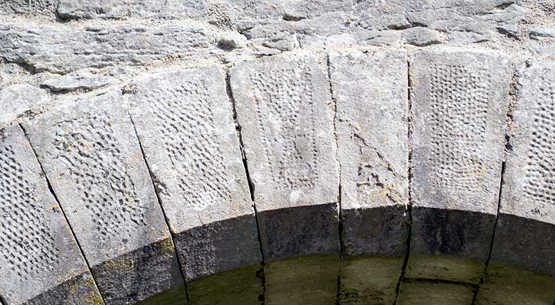 The dressed and punched stonework arch leading to the side chapel. Note the design of diagonal lines within a sub rectangular frame on one of the stones.